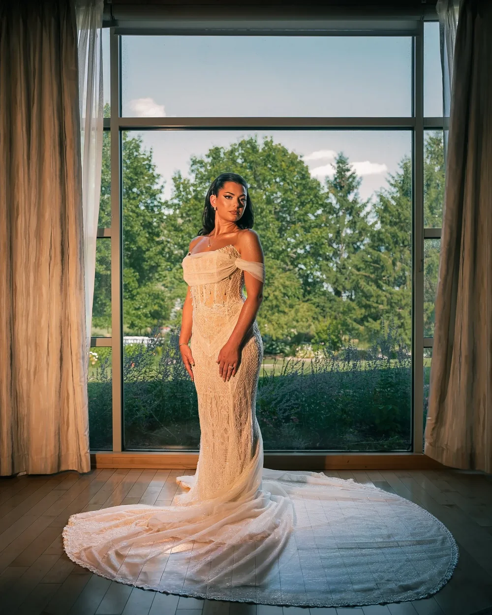 Bride in a beaded lace gown with a long train at a garden window, Turning Stone Resort Casino