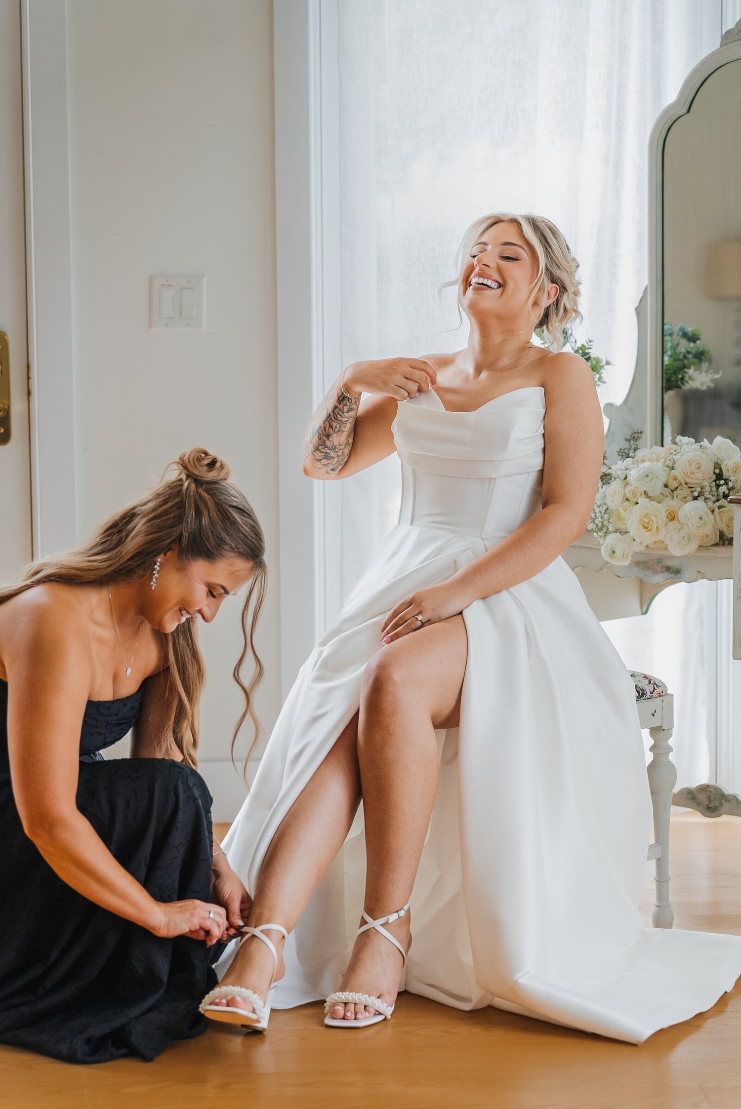 Bride having her shoes adjusted inside a bright Stonewall Estate getting-ready suite
