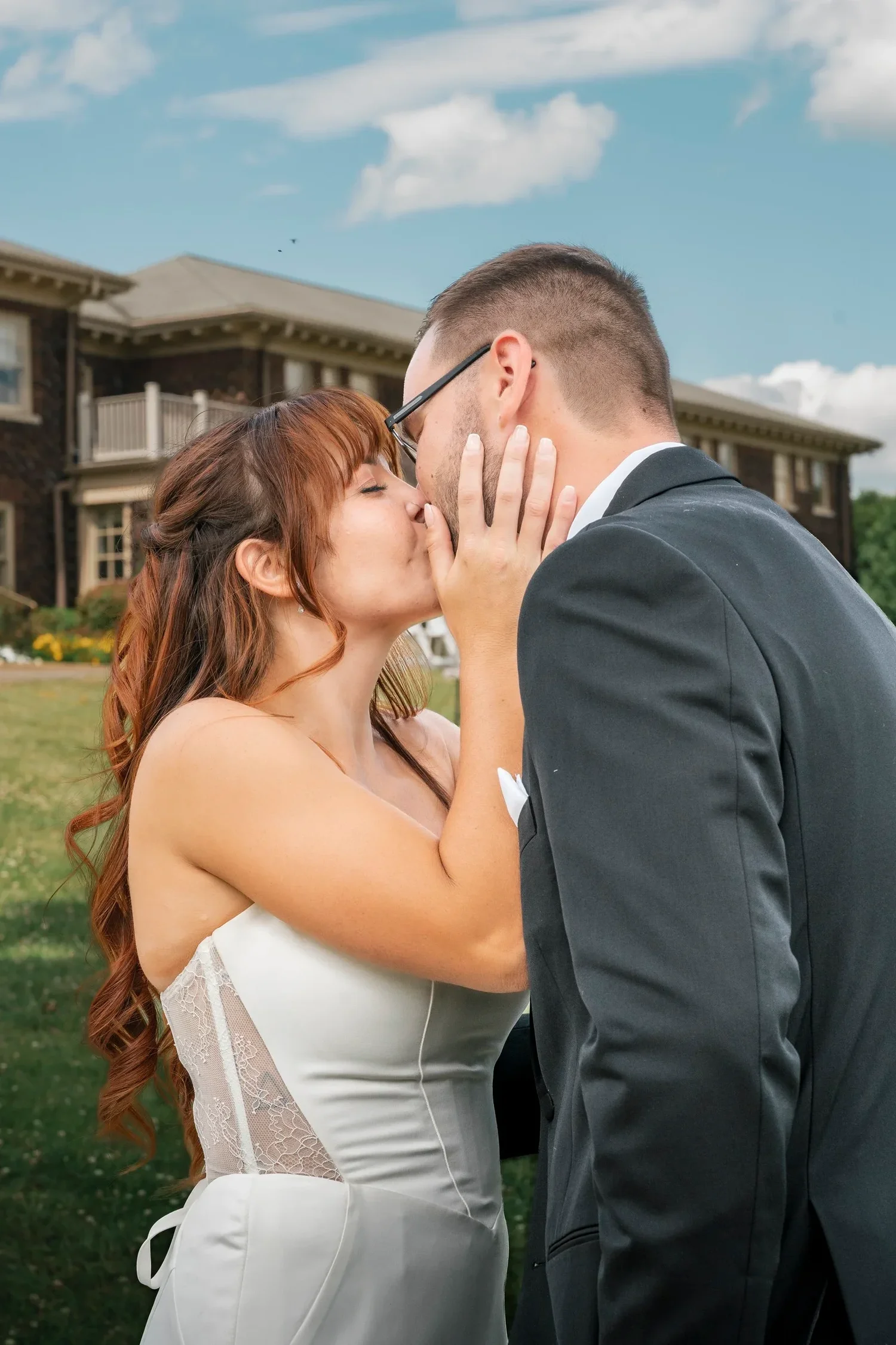 Danielle and Zach kissing on the lawn in front of the mansion at Traditions at the Glen