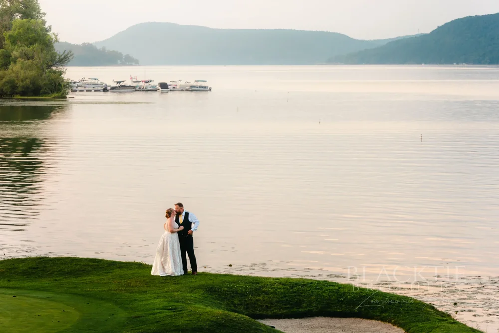 Amanda and Chris standing at the edge of the lawn above Otsego Lake in Cooperstown, near The Otesaga Resort Hotel