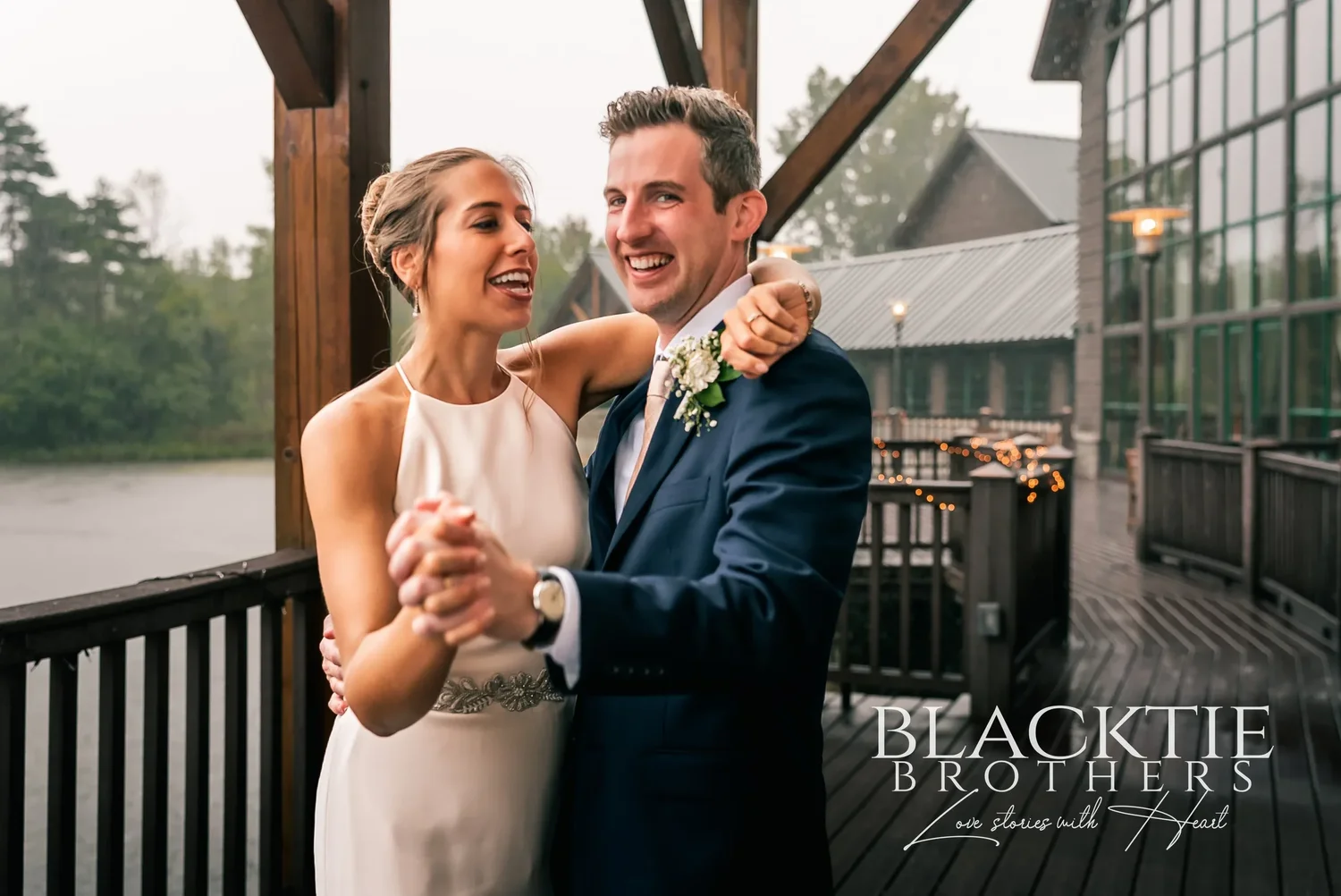 A laughing couple dancing on the deck at Allyn Lodge with the pond behind them.
