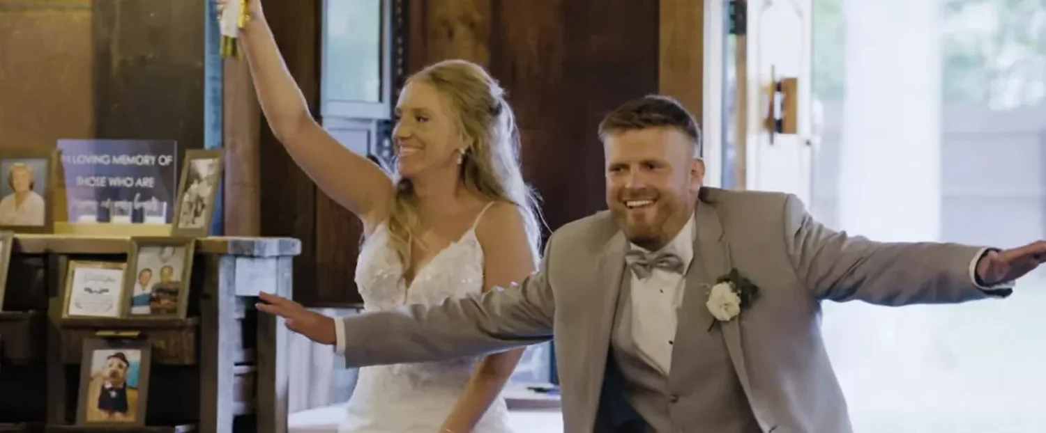 Jennifer and Alex bursting into the reception room at The Cannery for their grand entrance, both grinning, her arm raised