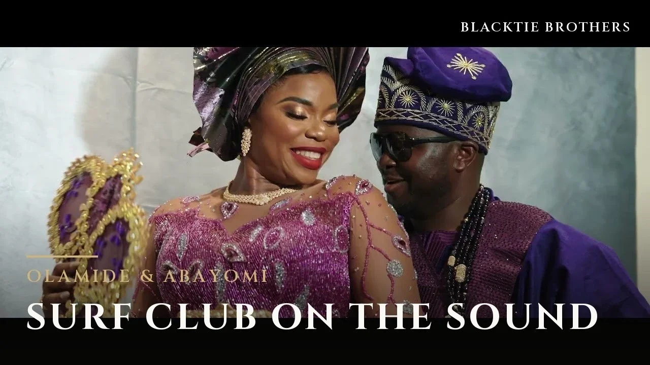 Olamide in a purple and gold head wrap and beaded lace, smiling and holding a gold-framed hand fan, beside Abayomi in a matching embroidered purple cap, with the title text Olamide & Abayomi, Surf Club on the Sound