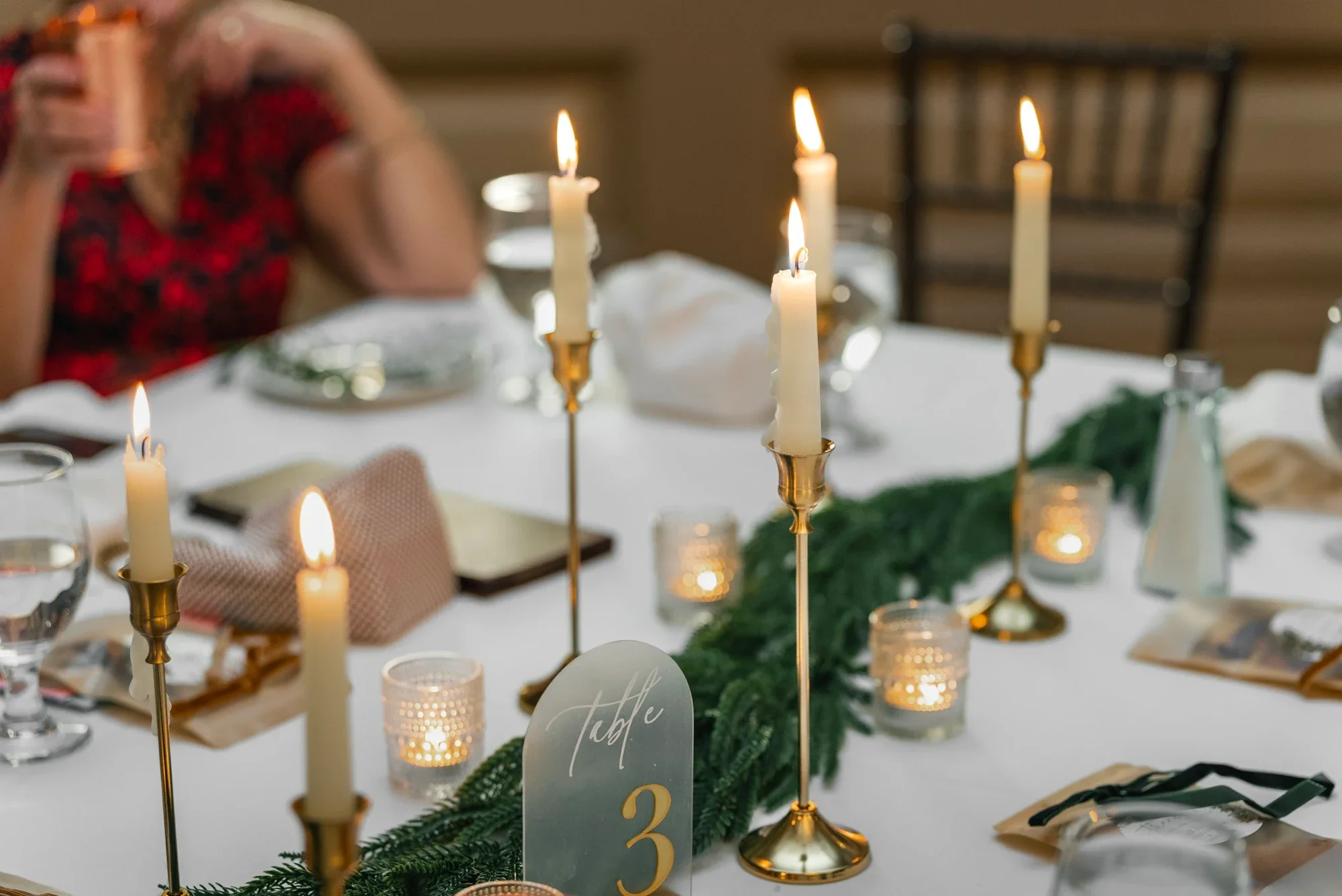 Taper candles, votives and a table number card on a reception table at Remlik’s.