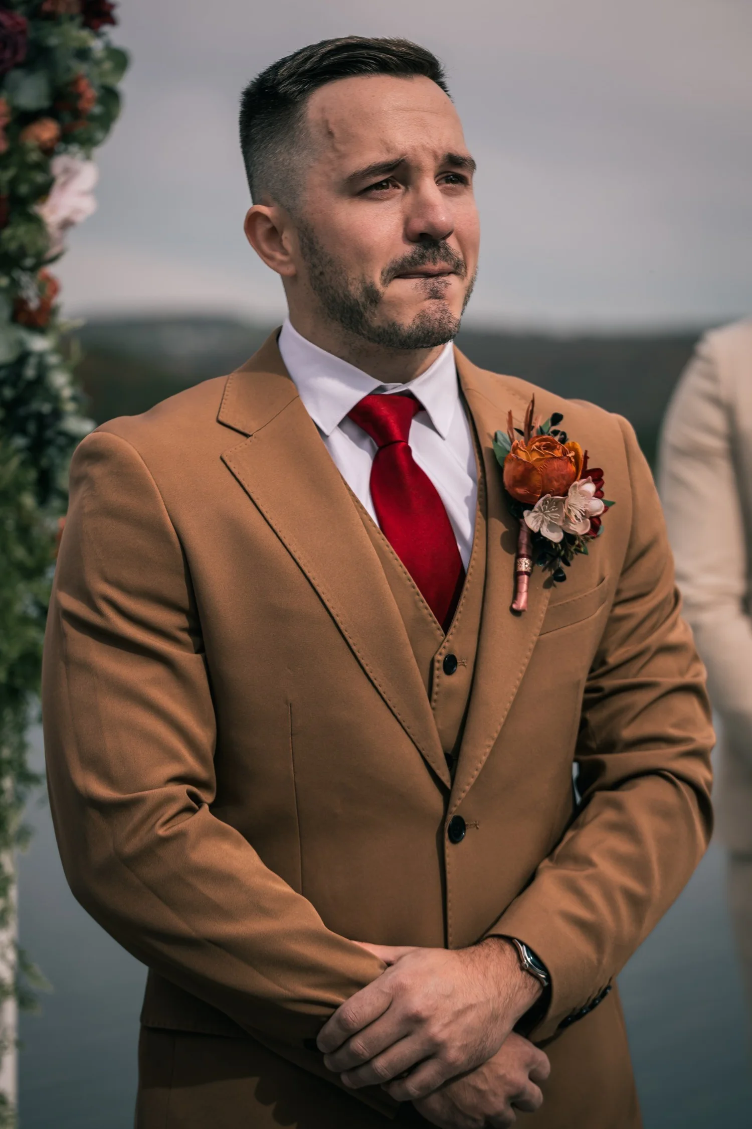 Vincent in a brown three-piece suit and red tie, watching the aisle