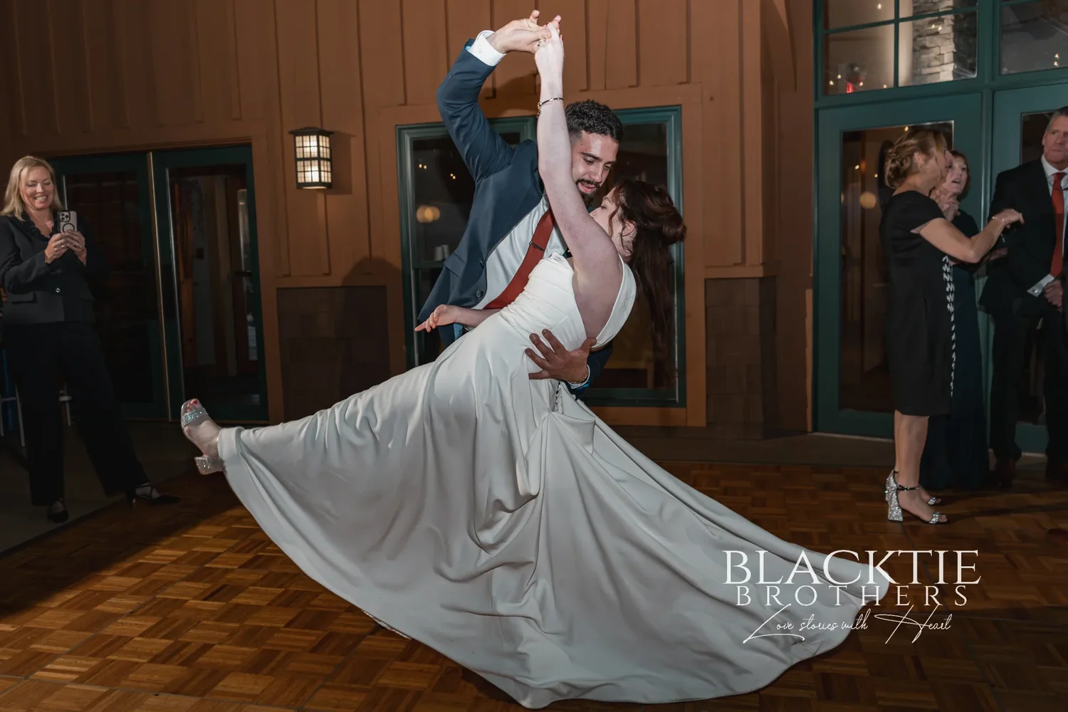 Gabe dipping Anya on the dance floor at Glenora, her dress swinging out, guests watching from the doorway