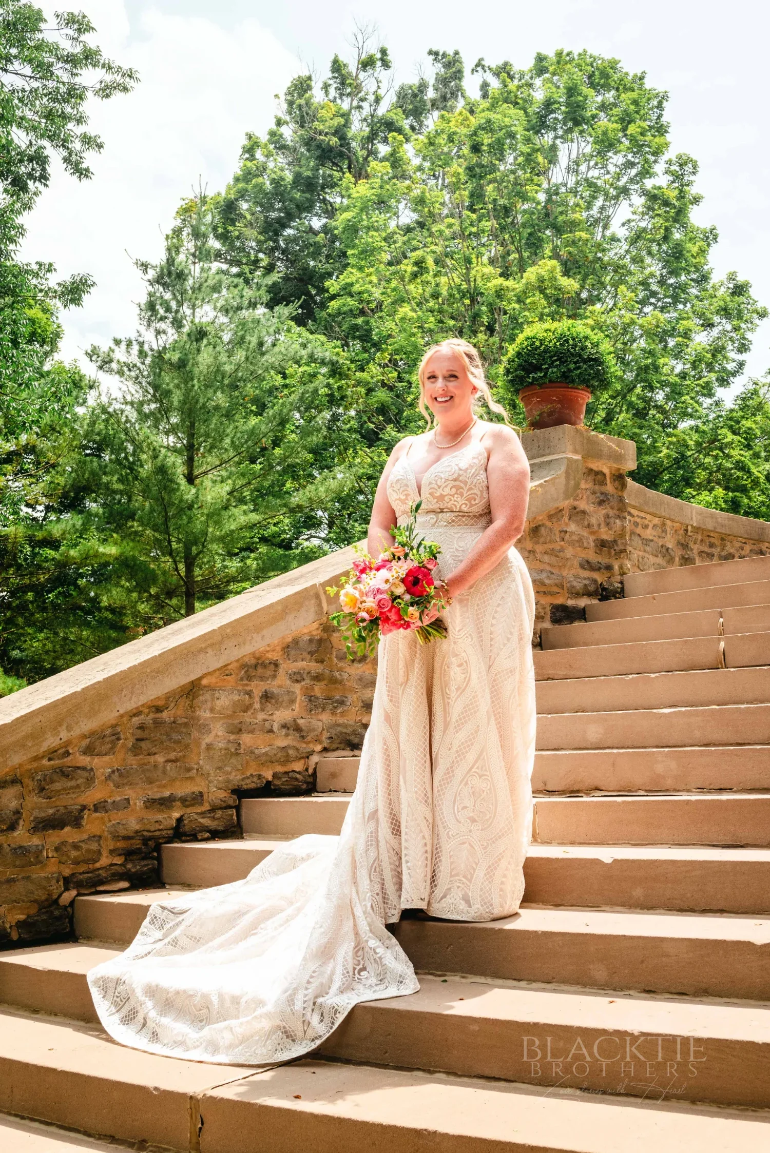 Amanda holding her bouquet on the curved stone steps at The Otesaga
