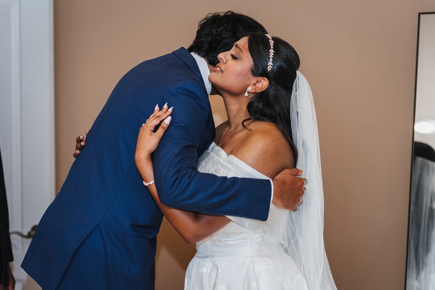 Natalia in her veil hugging a man in a navy suit before the ceremony