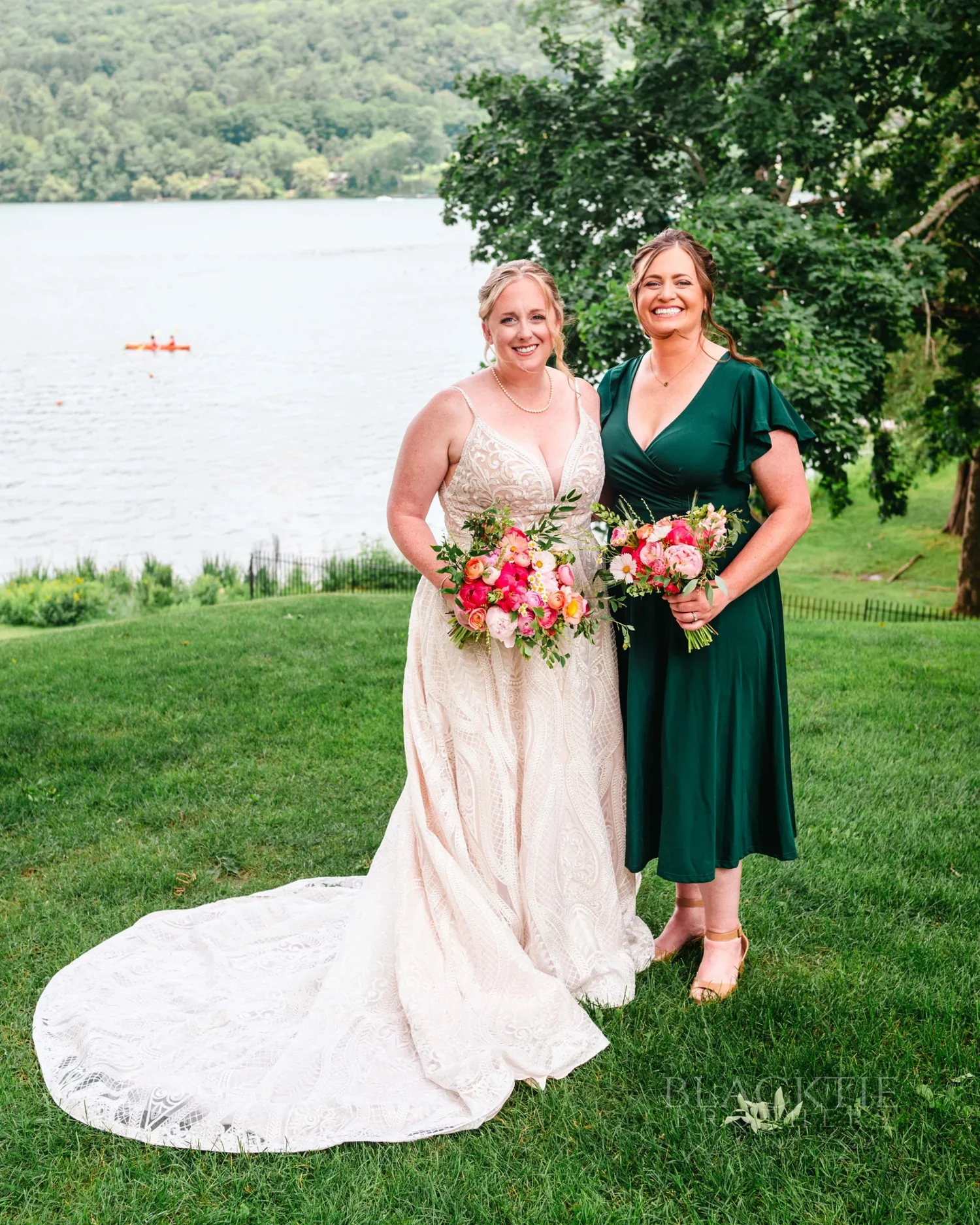 Amanda and a bridesmaid in an emerald dress on the lawn above Otsego Lake at The Otesaga