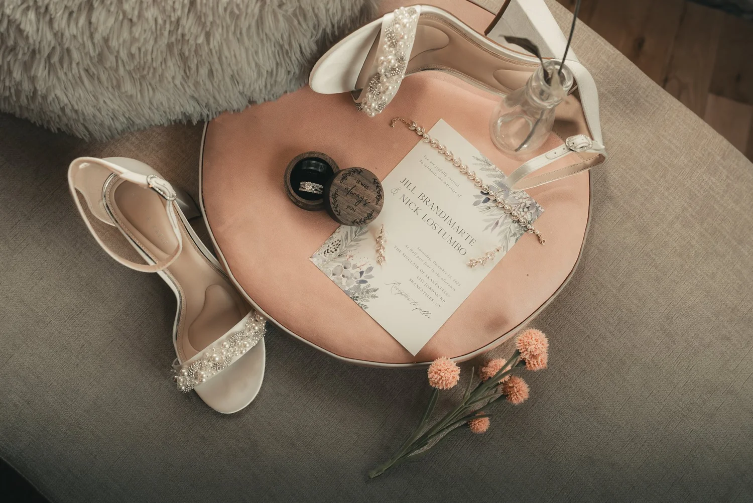 Jill’s wedding shoes, rings and printed details arranged on a blush-colored table at The Sinclair of Skaneateles