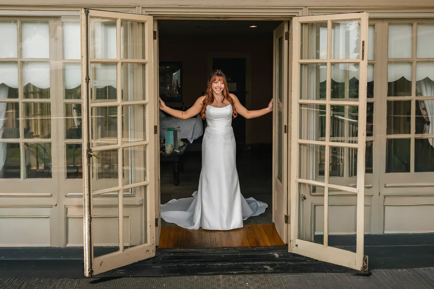 Danielle in her wedding dress standing in the open French doors of the mansion at Traditions at the Glen