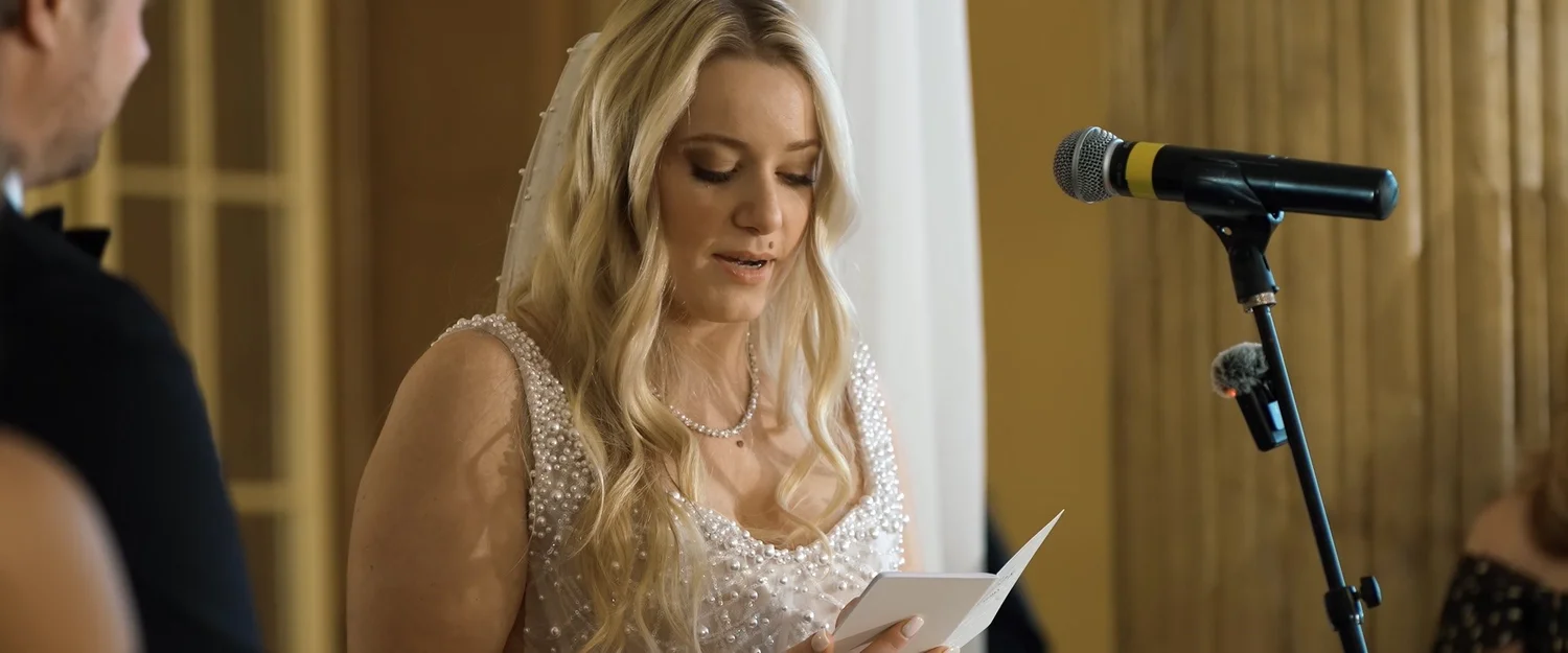 Catie reading her vows into a microphone during the wedding ceremony