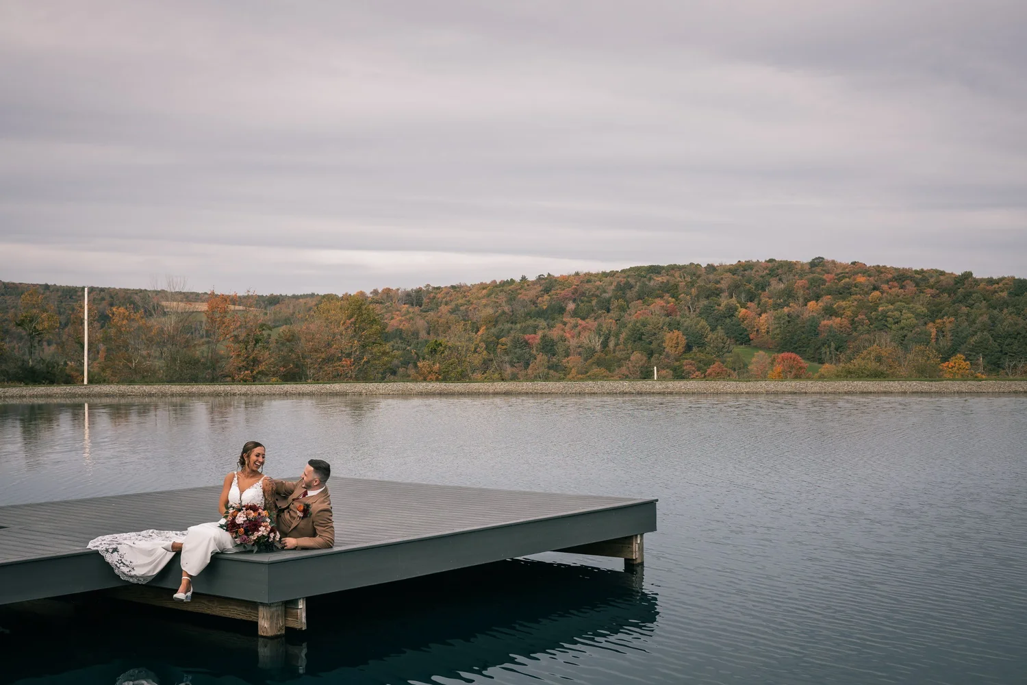 Heather and Vincent sitting together at the edge of the floating dock on the pond