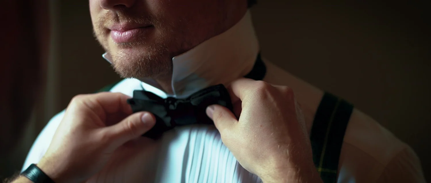 Brad adjusts his bow tie while getting ready for the wedding