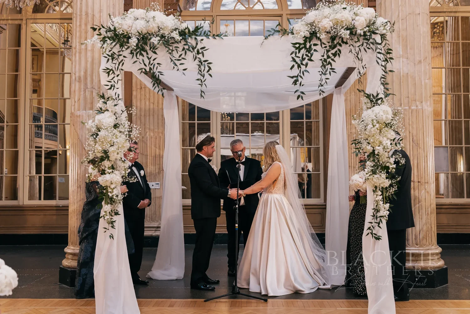 Catie and Brad under a white floral ceremony canopy at Marriott Syracuse Downtown