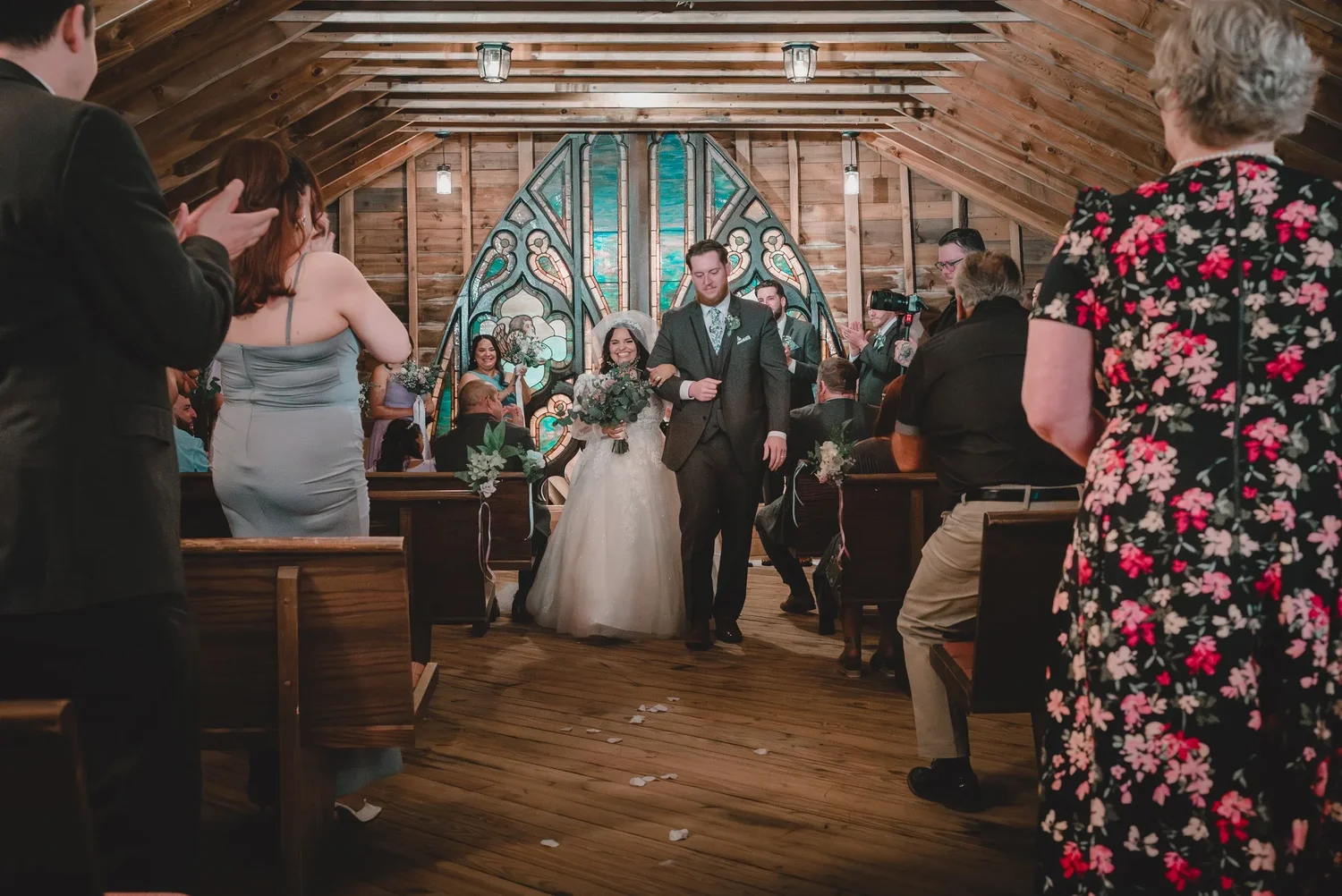 Jessica and Christian walking back up the aisle of the Loft Chapel after the ceremony, with guests standing on both sides