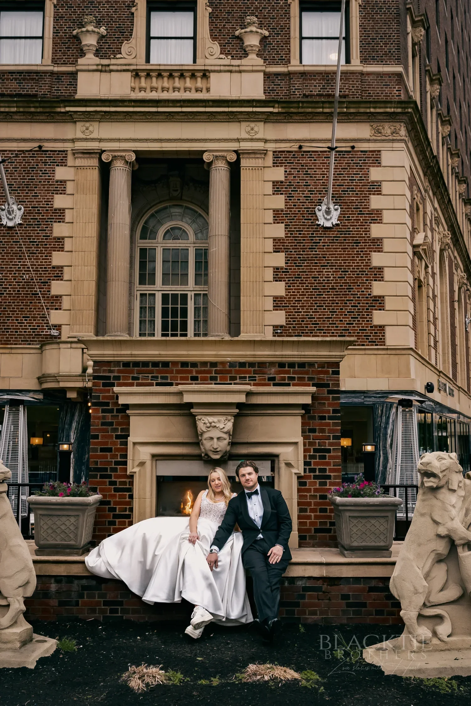 Catie and Brad posing at the carved stone entrance of the historic Hotel Syracuse facade