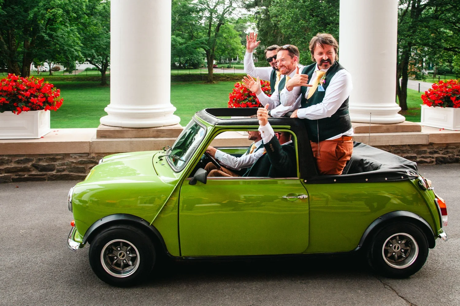 Groomsmen celebrating with a green Mini Cooper at The Otesaga entrance