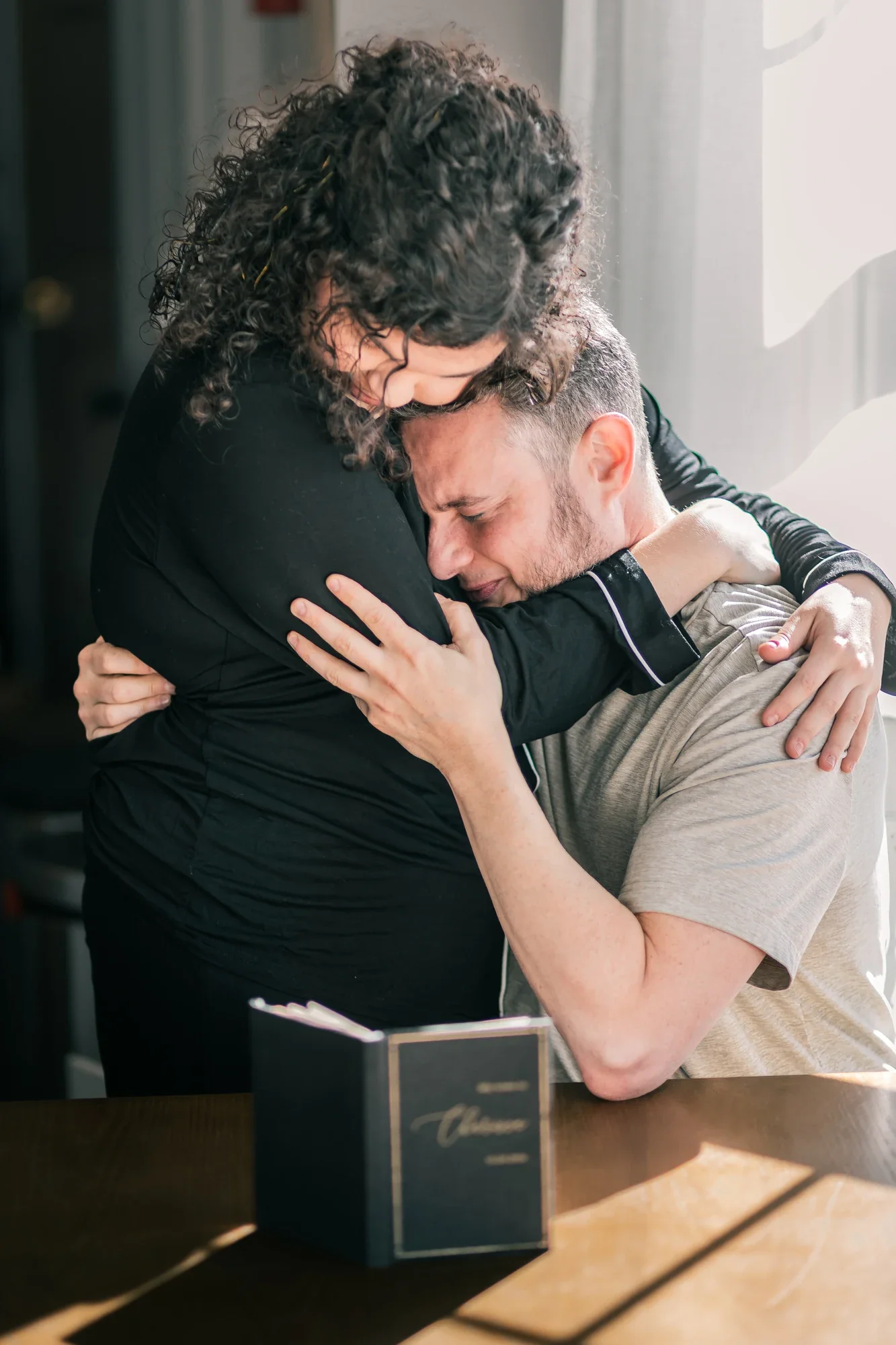 Andrew being embraced after reading Charissa's letter, the open letter in his hand