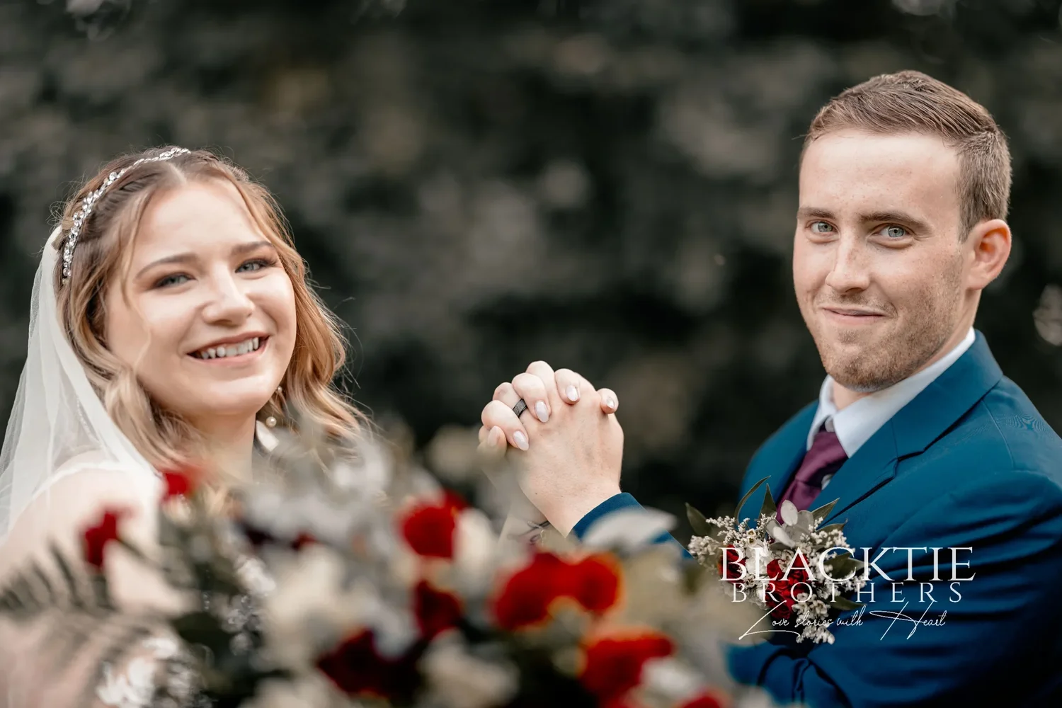 Jennifer and Jared just after the ceremony, hands clasped and raised together, both smiling, trees behind them