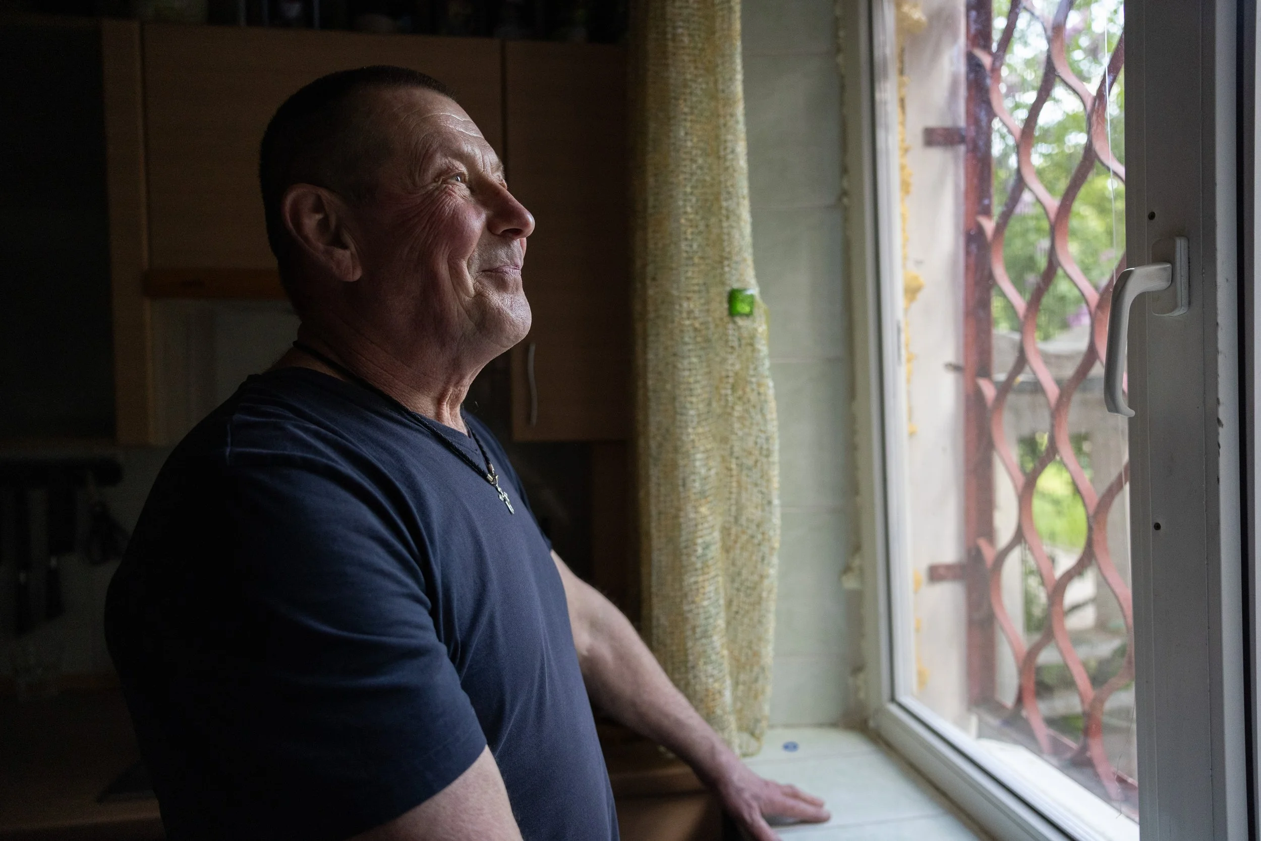 A resident in Ukraine standing beside an emergency replacement window installed by Insulate Ukraine