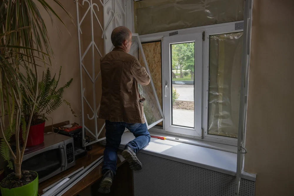 A Nikopol resident installing an Insulate Ukraine V3 self-install emergency window as Harry Blakiston Houston looks on.
