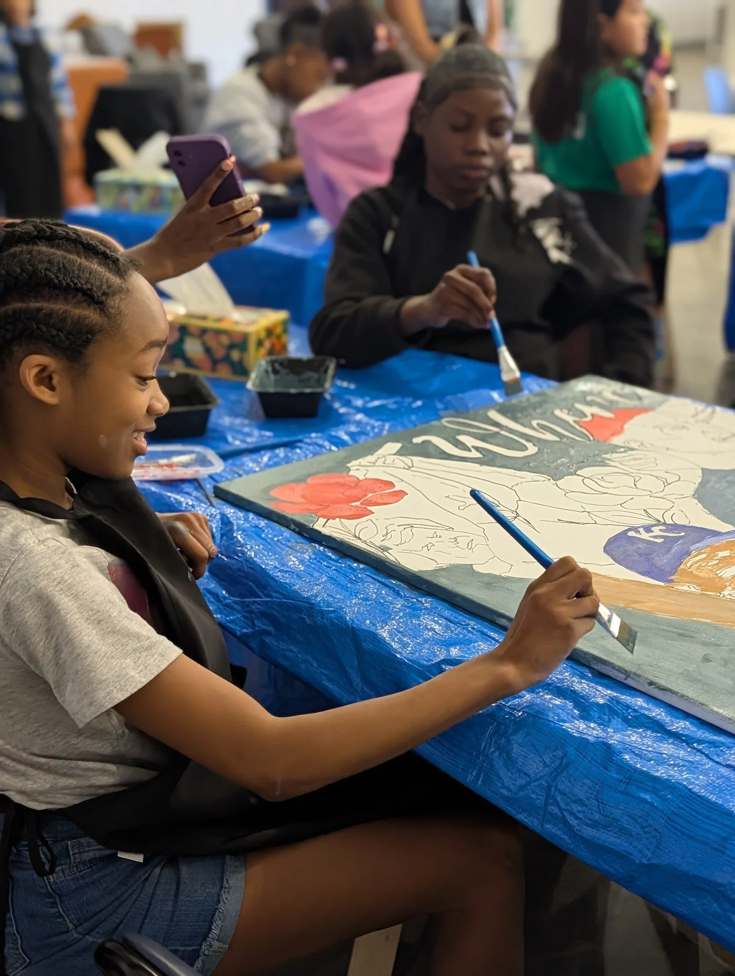 Young artists add painted details to a shared canvas at a YAI workshop.
