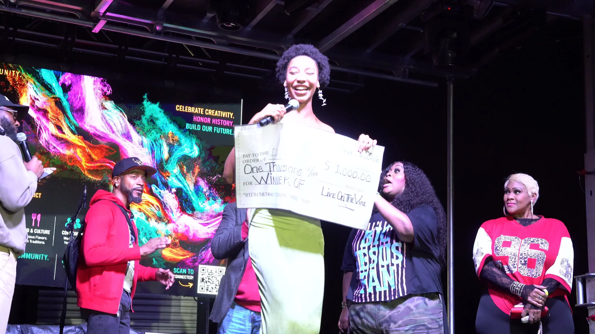 Daysia Reneau in a green dress holding her Live on the Vine winner's check at the 2026 festival