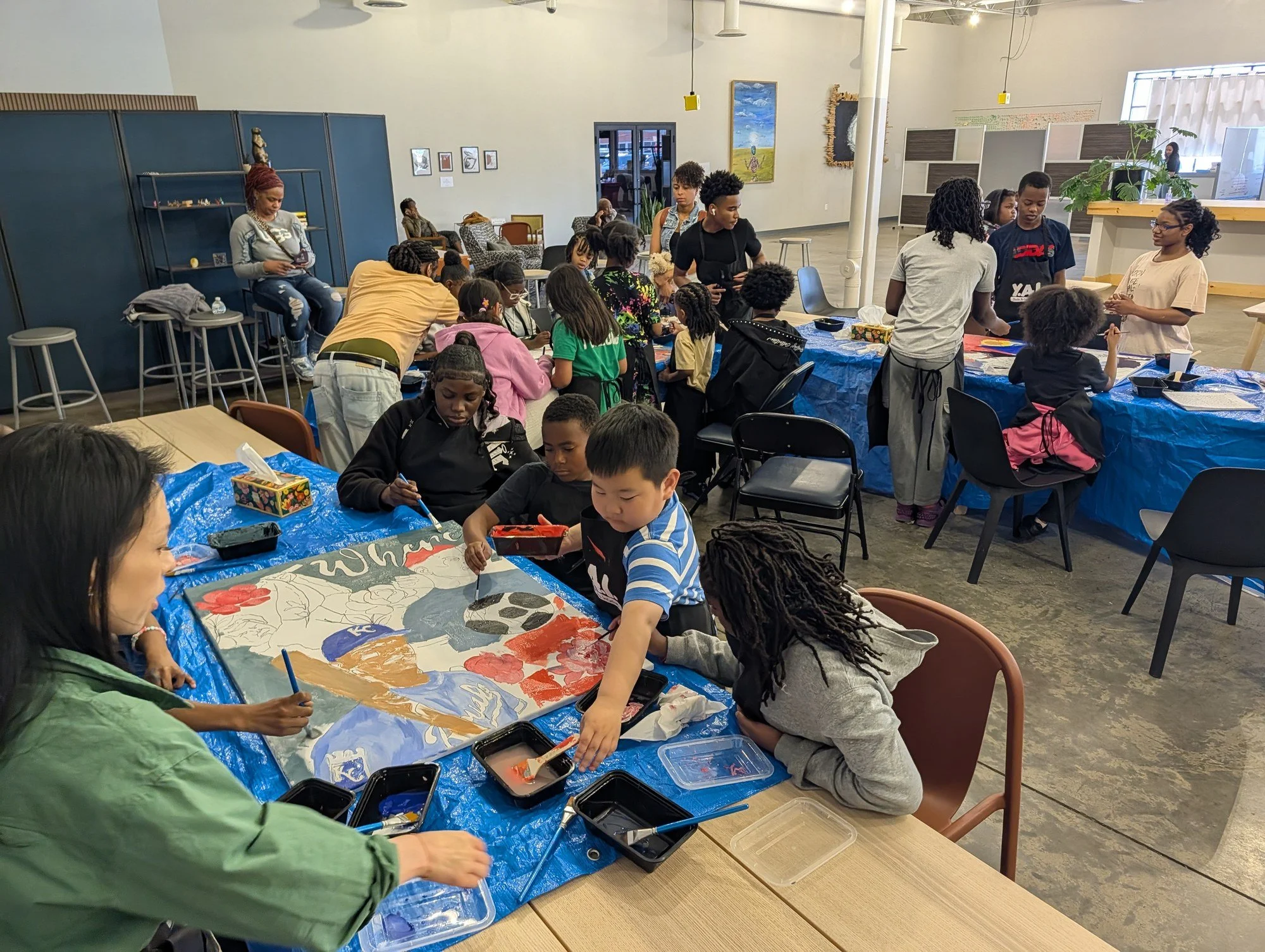 Children and teaching artists create a colorful collaborative painting during a previous YAI session.