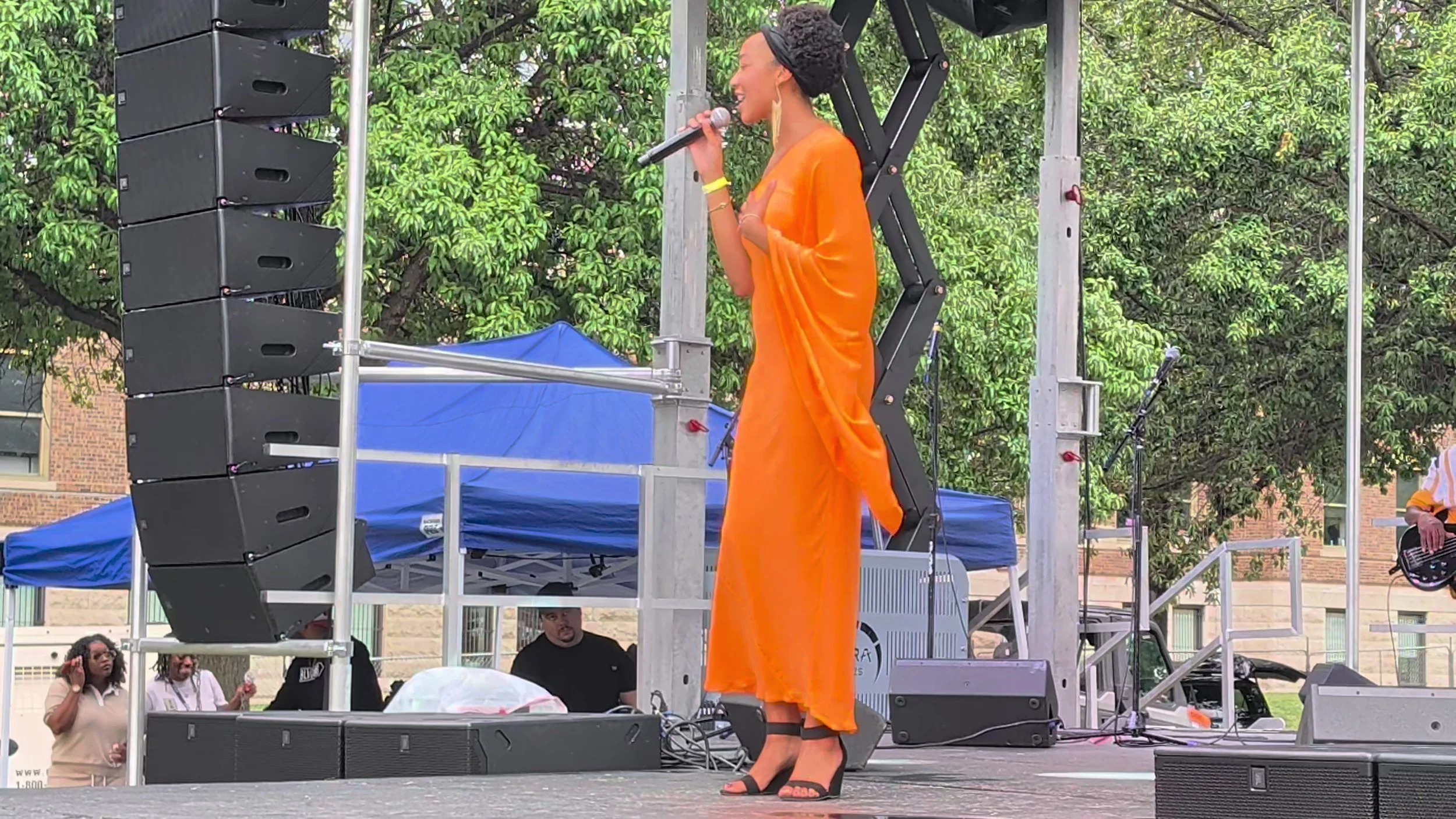 A vocalist in orange singing on the Live on the Vine stage.
