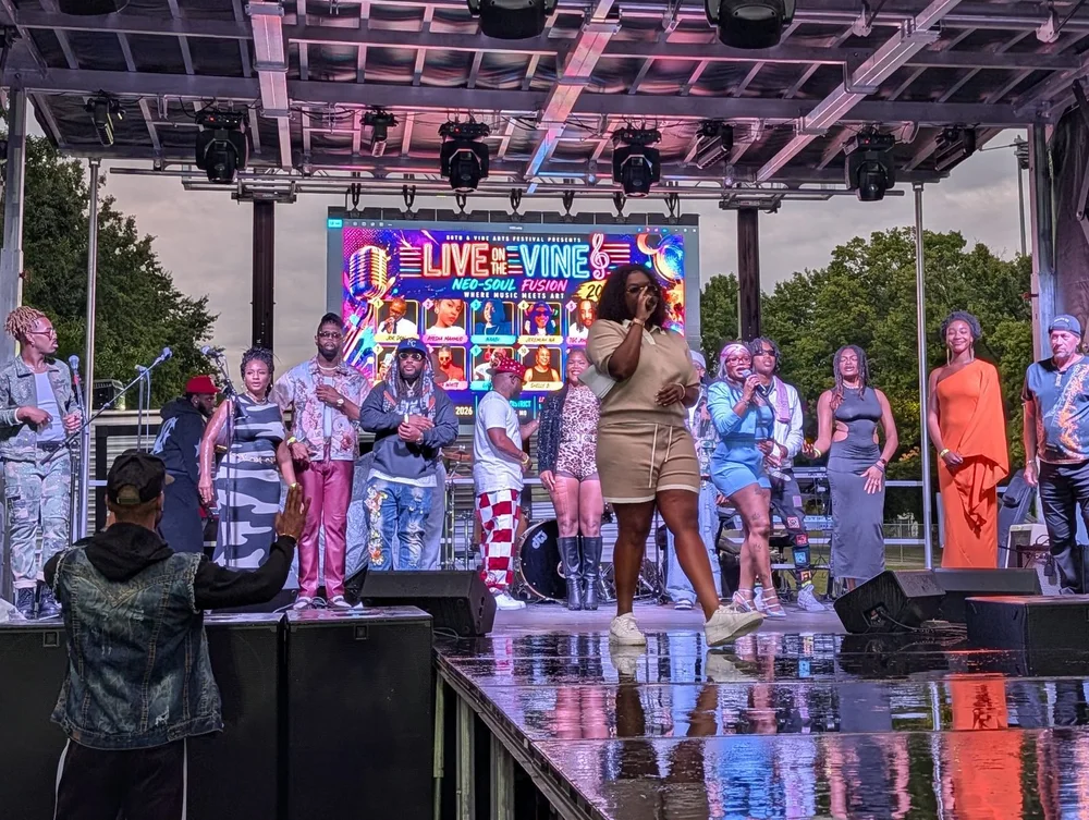 A singer performs in front of a smiling group on the Live on the Vine stage at the 2026 festival.