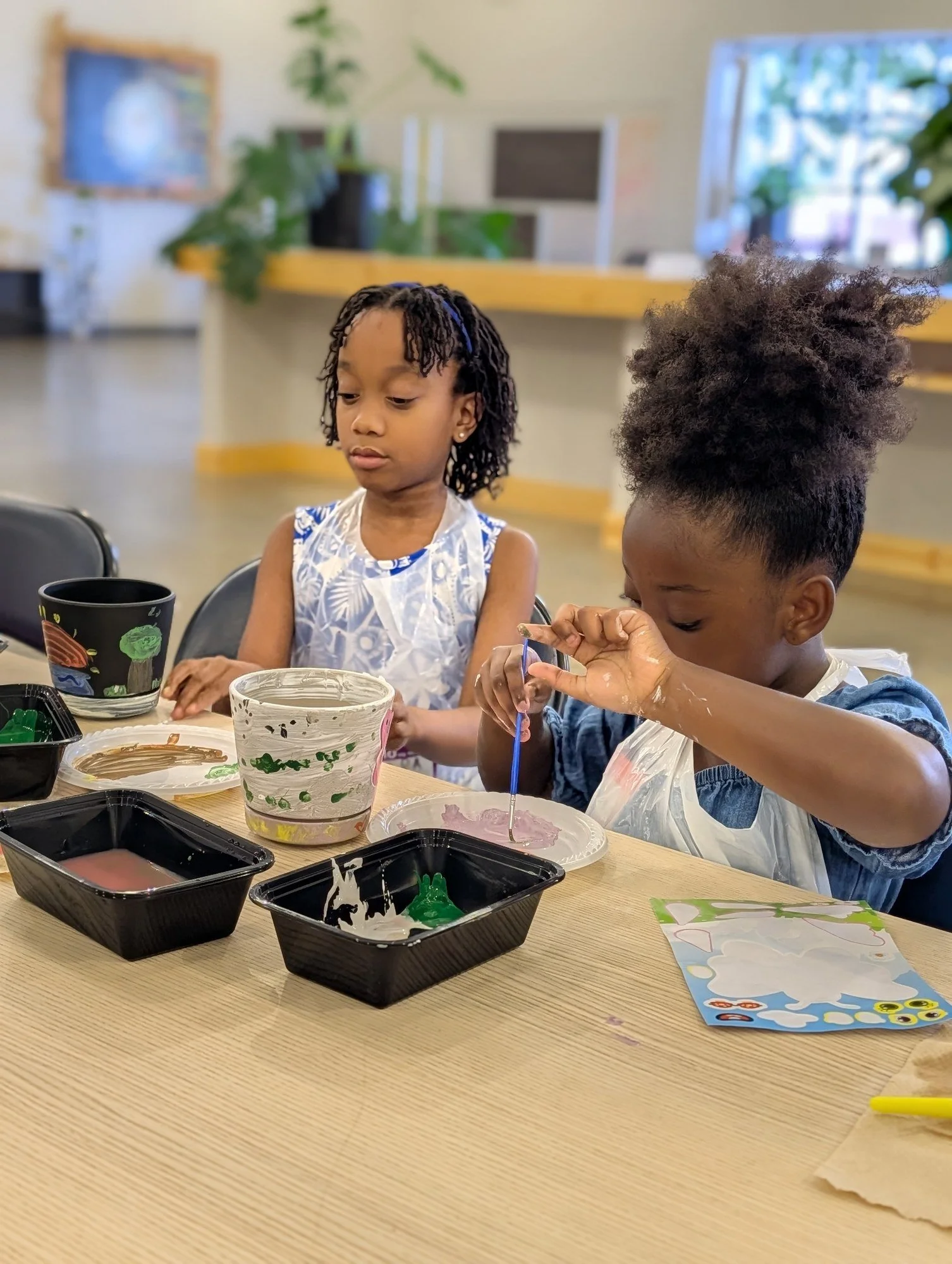 Young artists paint small containers together during a previous YAI workshop.