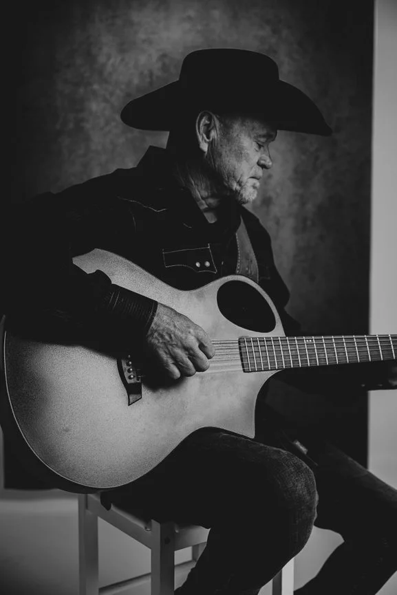 Black and white portrait of singer-songwriter Paul Staggs playing acoustic guitar