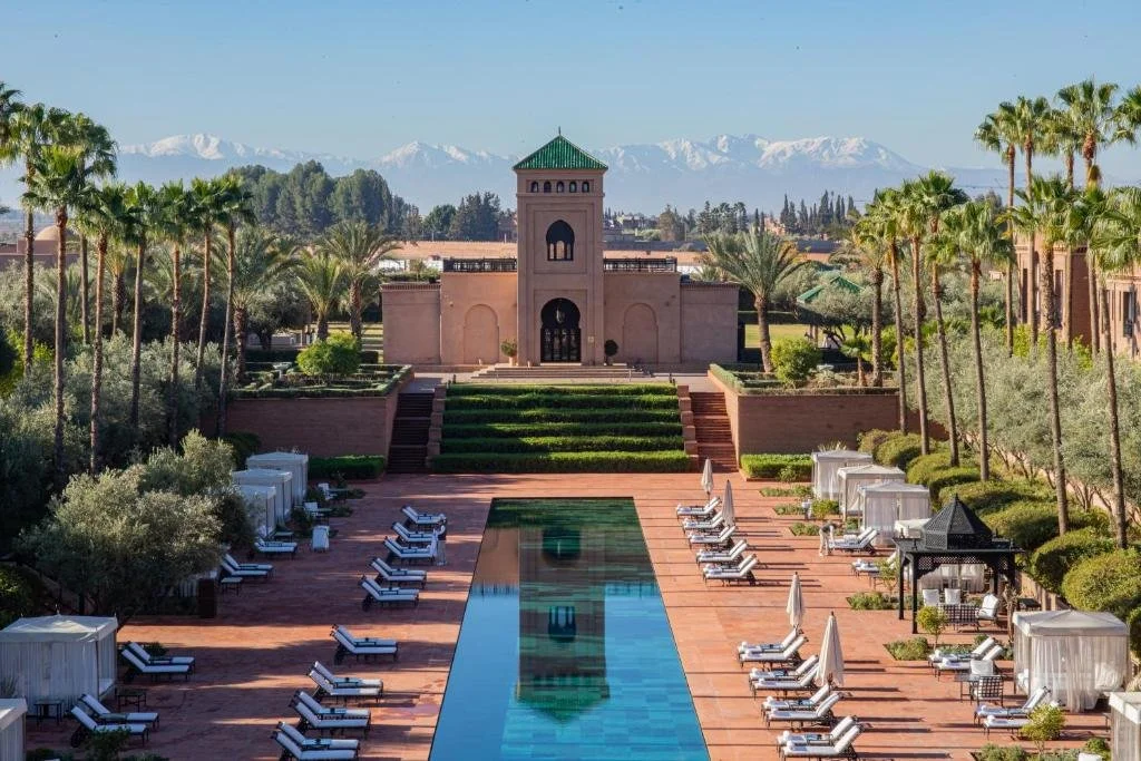 Selman Marrakech formal gardens and rectangular pool with snow-capped Atlas Mountains across the horizon