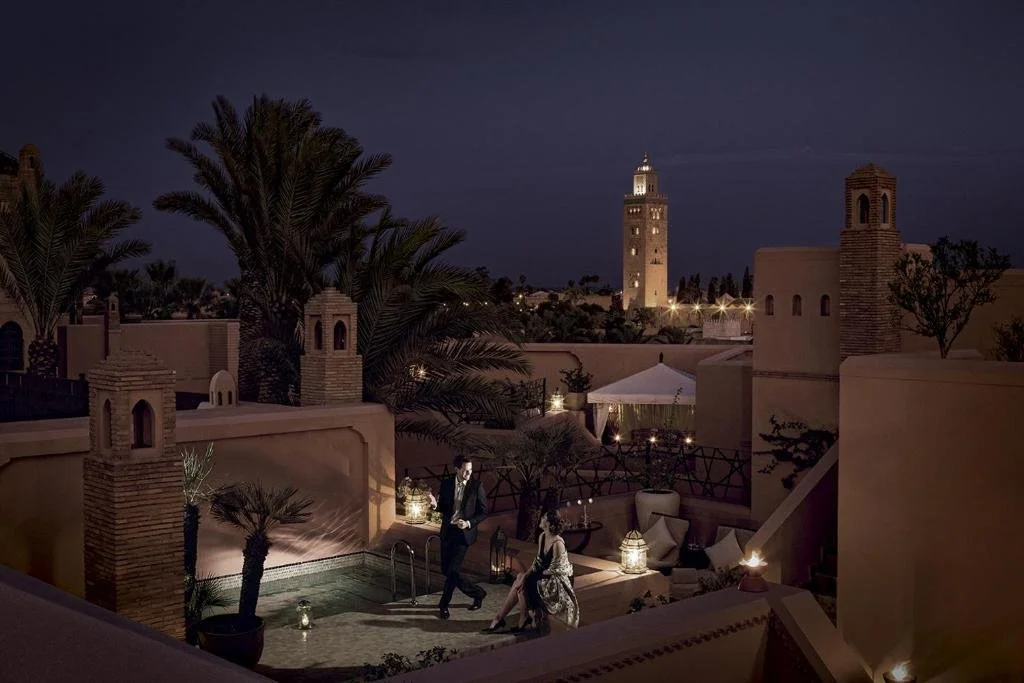 Royal Mansour Marrakech private riad rooftop terrace at night with the illuminated Koutoubia Mosque minaret above the medina rooftops