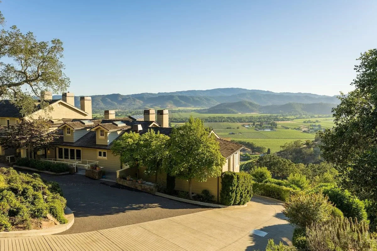Sttupa Estate Napa Valley hotel buildings with vineyard rows and Mayacamas Mountains behind