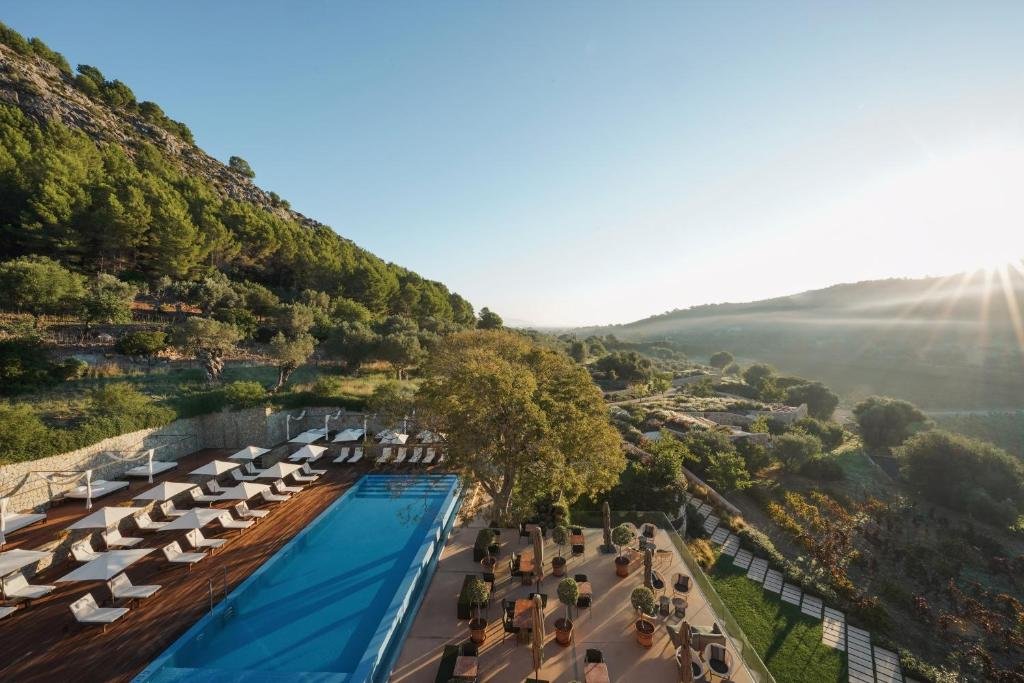 Son Brull Mallorca Pollença outdoor pool deck with white sun loungers and pine-covered Tramuntana valley at sunrise