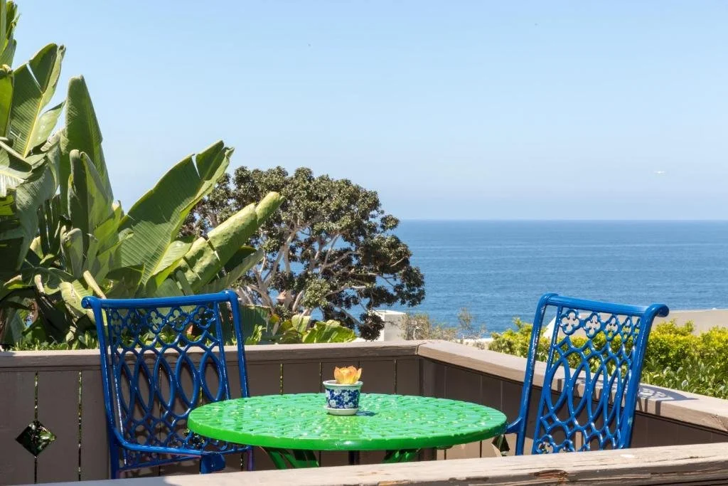 Casa Laguna Hotel and Spa Laguna Beach hillside terrace with blue iron chairs and Pacific Ocean view above tropical garden