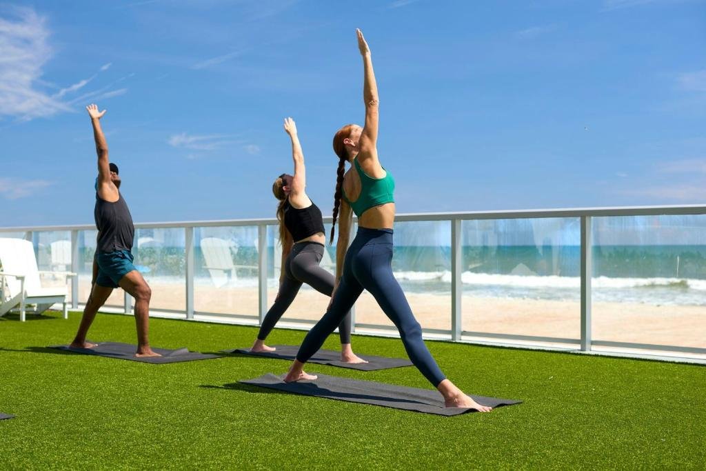 Renaissance Daytona Beach Oceanfront Hotel rooftop yoga class on grass terrace with glass railing and Atlantic Ocean in the background
