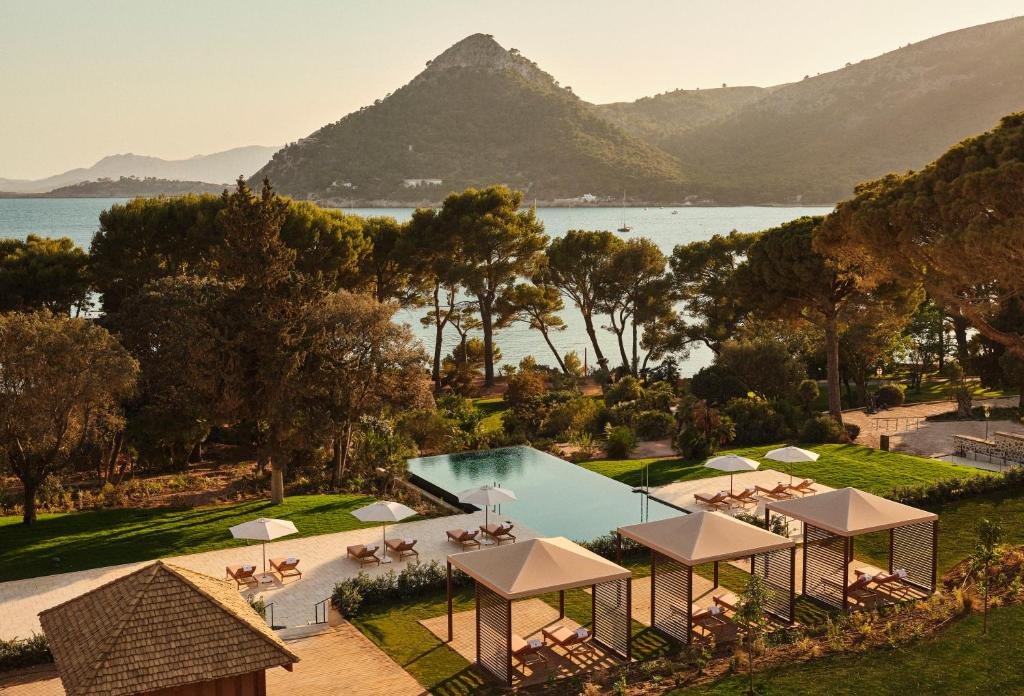 Four Seasons Resort Mallorca at Formentor Port de Pollença pool terrace with pine trees and mountain-ringed bay at golden hour