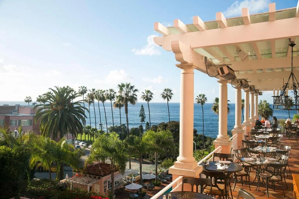 La Valencia Hotel La Jolla ocean-view terrace with white pergola columns and Pacific Ocean through palm trees