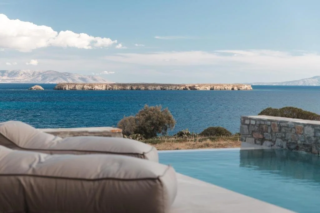 Poseidon of Paros Hotel Spa Paros pool terrace with beige daybed lounger overlooking Aegean Sea and flat rocky island