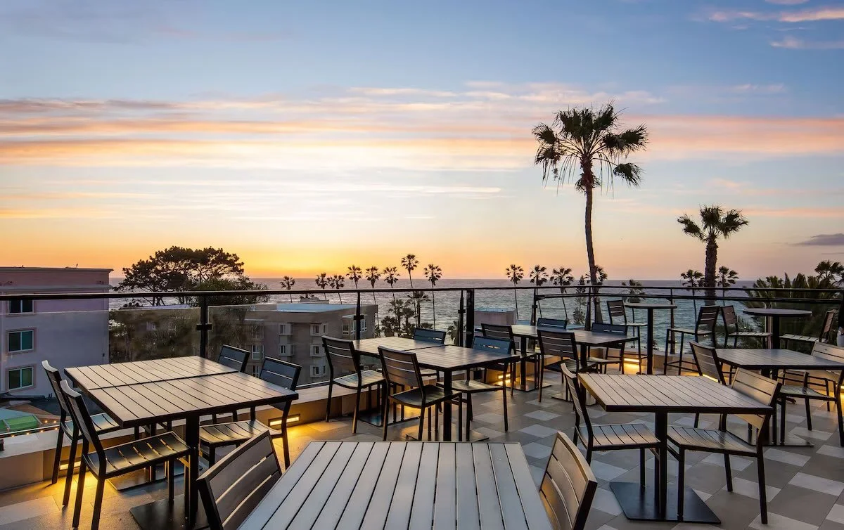 Cormorant Boutique Hotel La Jolla Birdseye rooftop terrace at sunset with dining tables and Pacific Ocean view