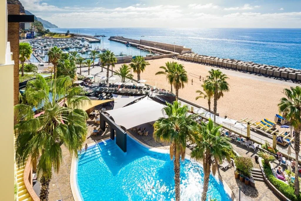 Calheta Beach Madeira hotel pool terrace with aerial view of golden sandy beach and marina