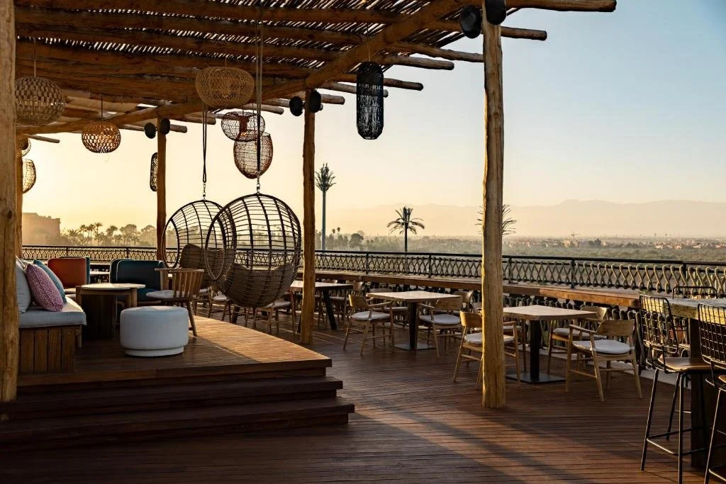 Nobu Hotel Marrakech rooftop terrace at golden hour with the Marrakech cityscape and Atlas Mountains on the horizon
