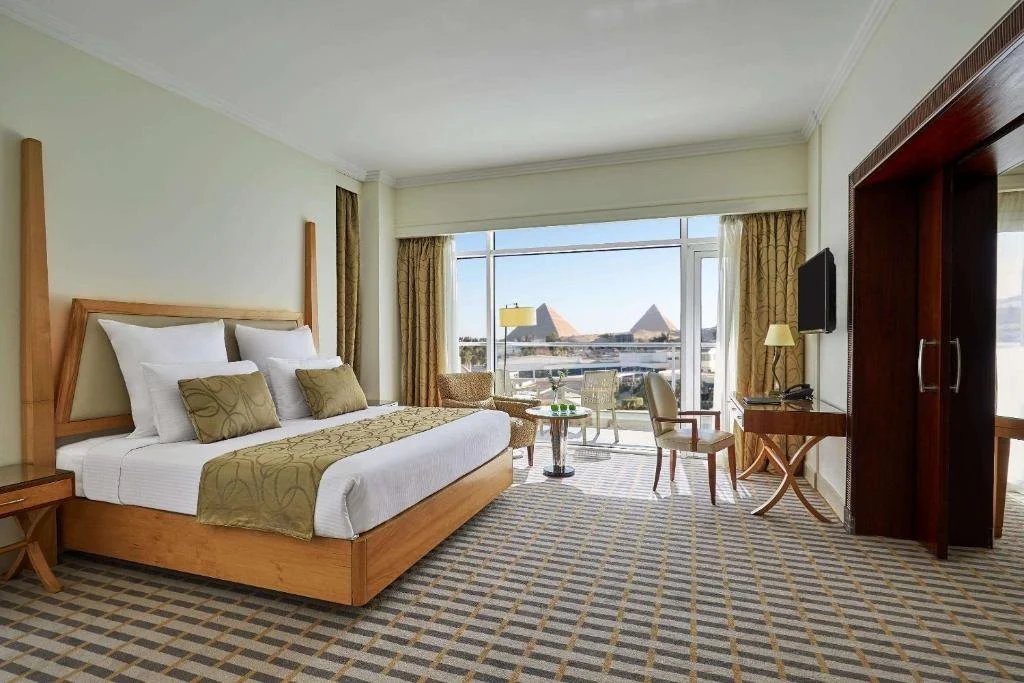 Steigenberger Pyramids Cairo hotel room with floor-to-ceiling window view of the Great Pyramid of Khufu and Pyramid of Khafre