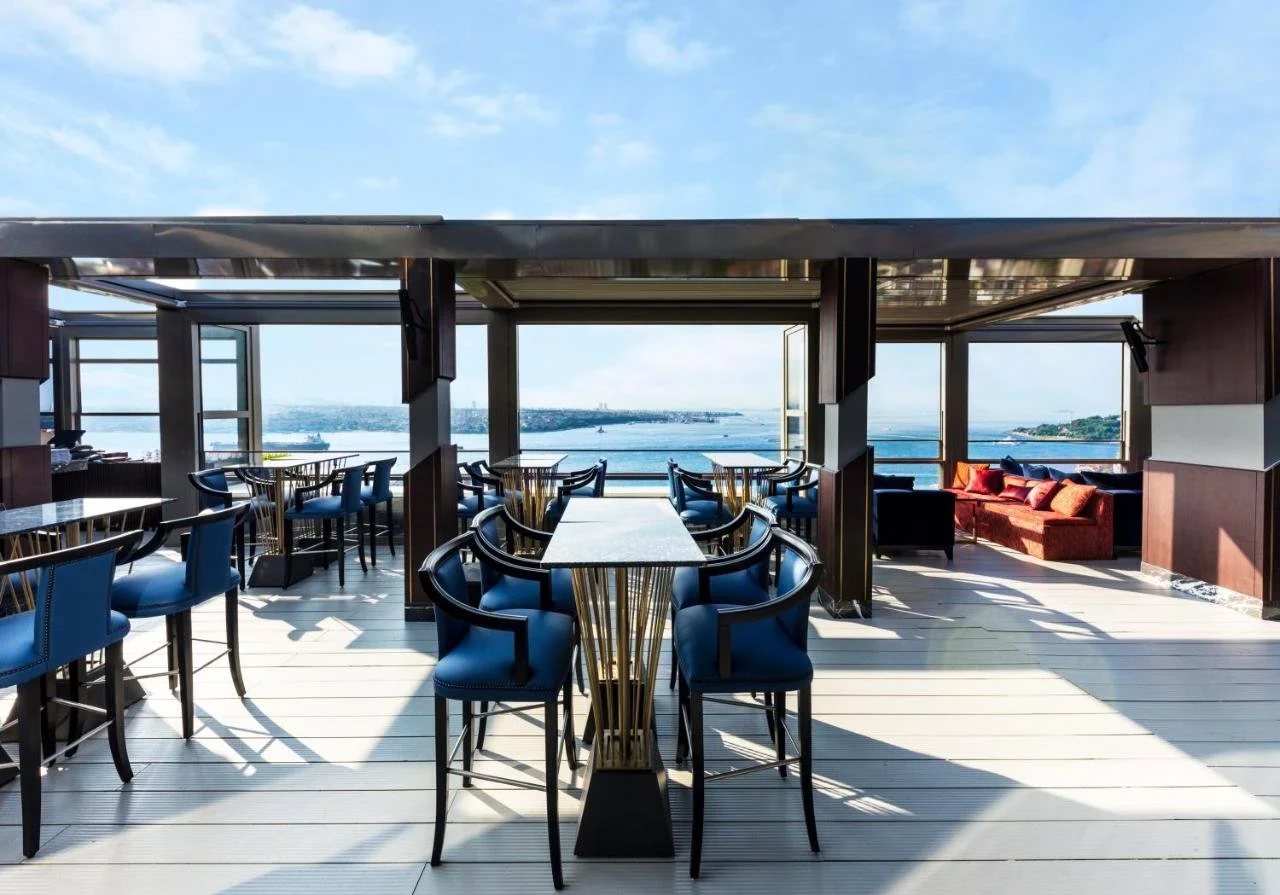 CVK Park Bosphorus Hotel Istanbul open-air rooftop restaurant terrace with navy chairs and panoramic Bosphorus view toward the Asian shore