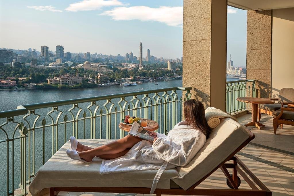 Four Seasons Cairo Nile Plaza private balcony with guest overlooking the Nile River and Cairo Tower on Gezira Island