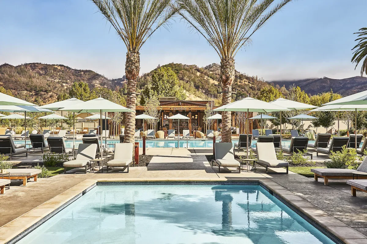 Solage Auberge Resorts Collection Calistoga pool and lounge area with tall palm trees and forested Palisades hills