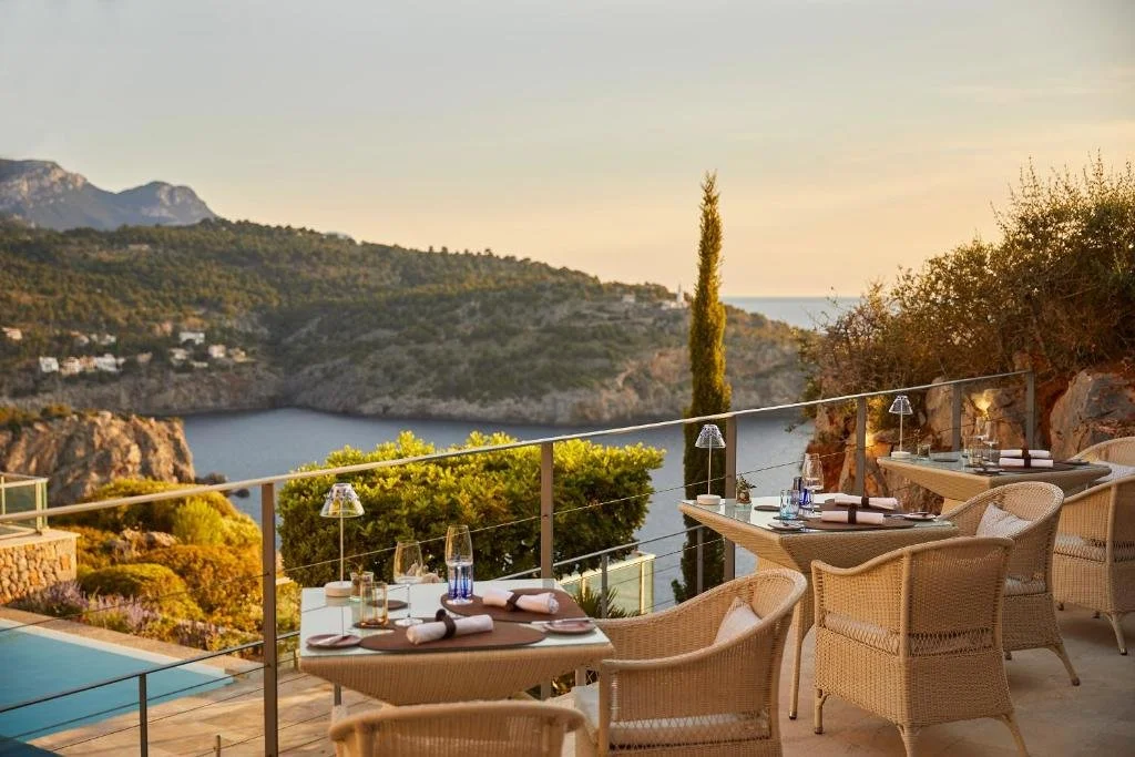 Jumeirah Mallorca Port de Sóller outdoor restaurant terrace with wicker chairs overlooking the bay and Tramuntana mountains at sunset